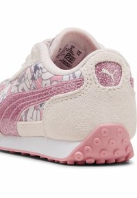 Zapatillas con una combinación de colores en rosa pastel y blanco, con un patrón floral, detalles de ante y un logotipo rosa brillante en el talón.