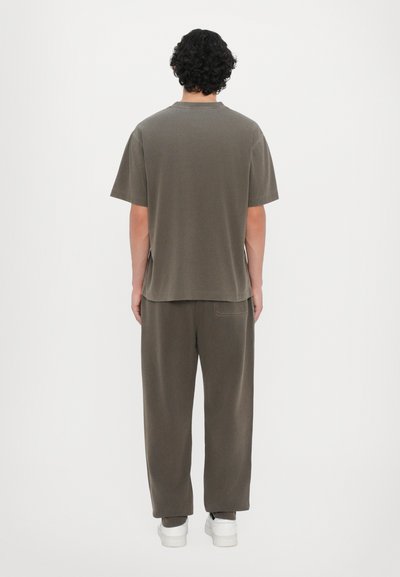 Oliven grøn t-shirt med kortærmer og løstsiddende bukser, lavet af blødt bomuld. Minimalistisk design med lige snit og sidesplitter.