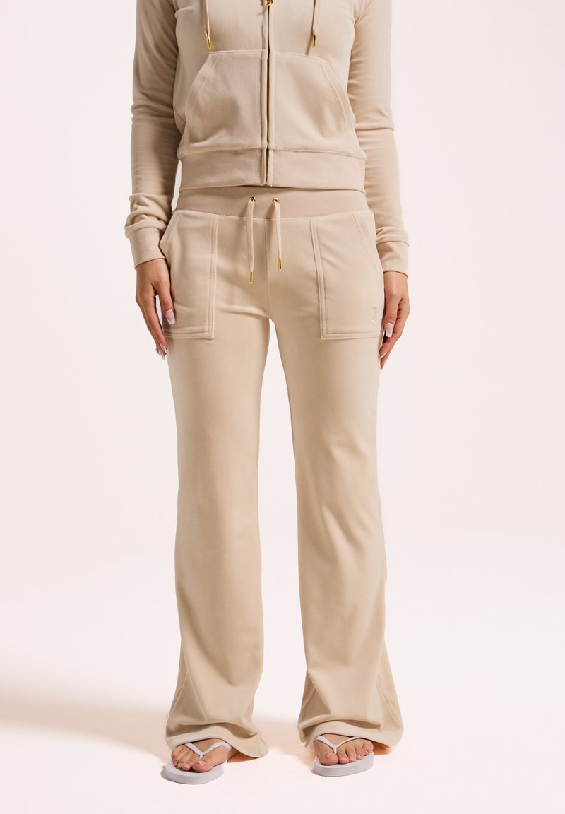 Ensemble de vêtements de détente beige comprenant un hoodie zippé avec poches avant et un pantalon assorti avec taille à cordon, fabriqué à partir d'un tissu doux et texturé.