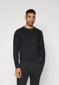 Sort sweatshirt med lange ærmer i blødt stof, med rund halsudskæring og ribbede manchetter. Subtil logo-detalje på brystet. Tætsiddende design.