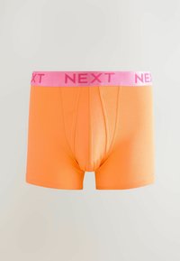 Narancssárga boxeralsó rózsaszín rugalmas derékkal, rajta a "NEXT" logóval. Az anyag sima, testhez simuló fazonú, elől nyitott.