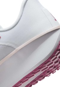 Scarpa sportiva bianca con superiore testurizzato, accenti rosa e suola in gomma con design di grip a motivo.