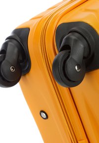 Valise rigide orange avec une finition texturée, équipée de roues et d'une fermeture éclair noires. Les détails notables incluent une forme lisse et courbée ainsi que des accents en métal.