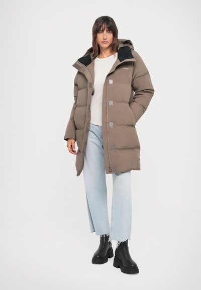 Padded brown parka with a hood, front zipper, and snap buttons. Worn over a light sweater and paired with light blue distressed jeans and black boots.
