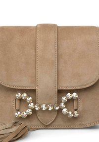 Bolso de ante beige con cierre de solapa, decorado con un adornos de cristal y un detalle de flecos en el lateral.
