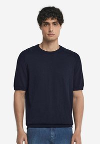 Marinblå kortärmad tröja i mjukt material, med rund halsringning och ribbade cuffar. Slät yta med subtila sömnadsdetaljer.