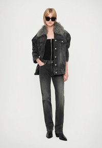 Μαύρο τζιν μπουφάν με γιακά από γκρι οικολογική γούνα, μαύρο τοπ, σκουρόχρωμα γκρι τζιν με ίσια γραμμή και μαύρα μποτάκια αστραγάλου. Σκούρα παλέτα χρωμάτων, μινιμαλιστικός σχεδιασμός.