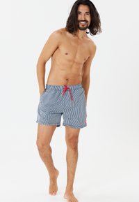 Blaue und weiße gestreifte Badeshorts mit ropem Kordelzug, Seitentaschen und Logopatch. Hergestellt aus leichtem, schnell trocknendem Material.