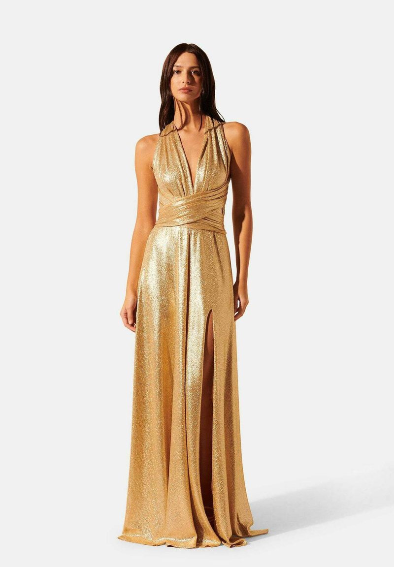 Robe de soirée dorée sans manches avec un décolleté en V profond, taille froncée et fente jusqu'à la cuisse, présentant une texture métallique scintillante.