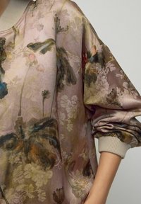 Vloeiende blouse met bloemenpatroon in zachtroze en gedempte tinten, met een ronde halslijn, volumineuze mouwen en geribde manchetten.