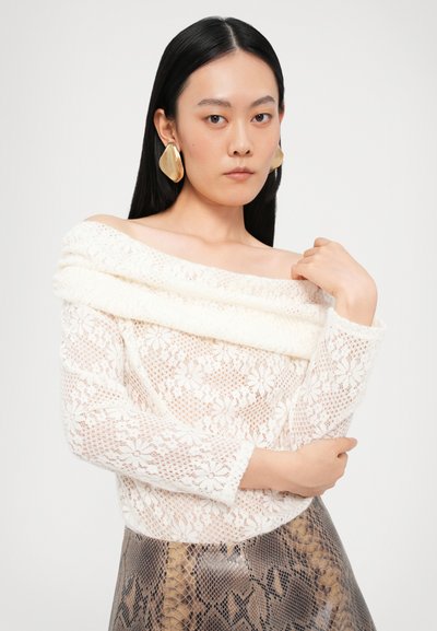 Hvit blonder off-shoulder topp med blomstermønster, teksturert kremfarget halslinning, lange ermer, sammen med et semitransparent mønstret skjørt.