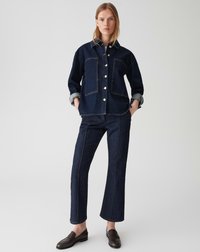 Veste en denim indigo avec deux poches avant et boutons argentés, associée à un pantalon en denim droit. Texture lisse, manches retroussées et design simple.