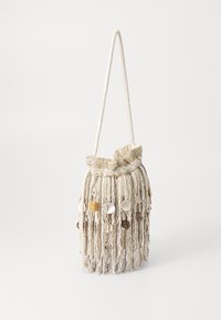 Fringe-laukku, jossa on kudottu runko vaalean beigen ja kerman värisenä, ja joka sisältää roikkuvia koristeita sekä olkahihnan. Elegantti, teksturoitu muotoilu.