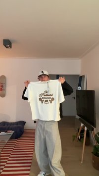 Short-sleeve white t-shirt with brown logo text "Professional Social Club Berlin," cotton material, loose fit, held by a person.