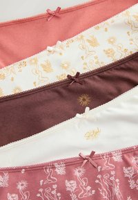 Cinq sous-vêtements féminins soigneusement empilés en tons rose, blanc et marron avec des nœuds et des imprimés soleil et fleurs.