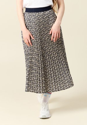 Gonna midi plissettata con base blu navy, caratterizzata da un motivo floreale in crema. Vita elastica e tessuto leggero; indossata con sneakers bianche.