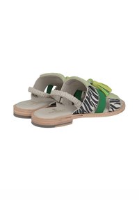 Sandali verdi con motivo a righe zebrate, dotati di una parte superiore morbida, cinturino regolabile e suola in sughero testurizzata. Presentano un elegante pon-pon verde decorativo.