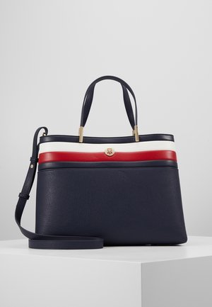 Bolso azul marino con rayas horizontales blancas y rojas, dos asas, una correa para el hombro desmontable y un pequeño emblema de logo dorado.