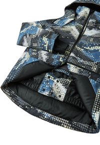 Chaqueta colorida con un patrón de lunares azules, negros y blancos, que presenta un cierre con cremallera, dobladillo elástico y una textura de tela brillante y elegante.