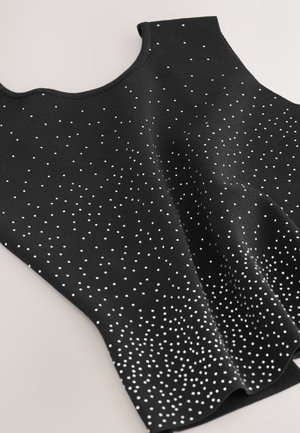 Crni pleteni top sa okruglim izrezom i uzorkom bijelih točkica po cijeloj površini, stvarajući teksturirani i moderan dizajn.