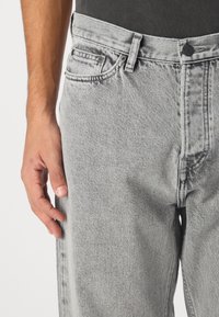 Hall ühed sirged denim teksased, millel on nööpe sulgemine, viis taskut ja diskreetne tekstuuriefekt.