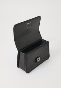 Pochette rectangulaire noire avec un devant en maille texturée, des côtés en cuir lisse et un fermoir carré en argent. L'intérieur ouvert offre un espace suffisant.