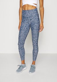 Höga, blå mönstrade leggings i elastiskt material med en strukturerad design och slim fit, i kombination med ljusblå sneakers.