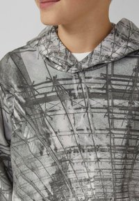 Felpa con cappuccio grigia con stampa fotografica di linee e dettagli strutturali, dotata di coulisse e tessuto morbido.