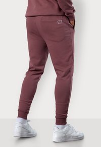 Bordeauxfarbene Sweatpants aus weichem Material, mit schmaler Passform, elastischen Bündchen und einer Gesäßtasche mit dezentem Logo-Detail.
