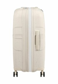 Valigia rigida di colore beige chiaro con righe orizzontali e una cerniera bianca. Presenta una maniglia laterale e due ruote nere per la mobilità.