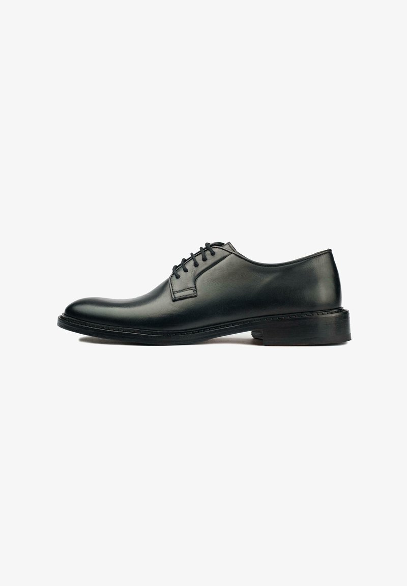 Black leather oxford shoe with a smooth finish, rounded toe, lace-up closure, and a low, textured rubber sole. Minimalistic design.