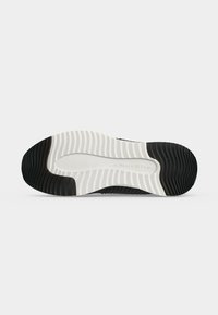 Semelle de chaussure en caoutchouc noir et blanc avec motif rainuré et le nom "Marc O'Polo" embossé au centre sur un fond gris uni.
