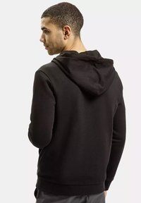 Czarna bluza z kapturem o miękkiej teksturze, z kapturem na sznurku, długimi rękawami i ściągaczami, przedstawiona z tyłu.