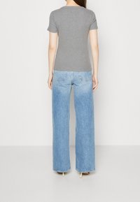 Grå t-shirt med kort ärm i kombination med ljusblå vida jeans. Tyget verkar mjukt; jeansen har en lös passform och fransad fåll.