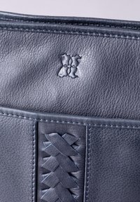 Dark blue leather handbag featuring a textured surface, a woven accent on one side, and a subtle embossed logo.
