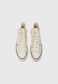 Höga sneakers i krämfärgad canvas med blommönster, vita snören, gummitåhätta och svart trim längs sulan.