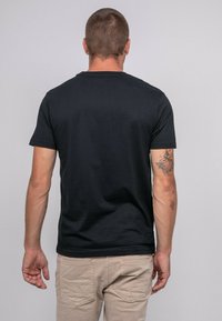 T-shirt noir à manches courtes en coton doux, présentant un design classique à col rond et une texture lisse, vu de dos.