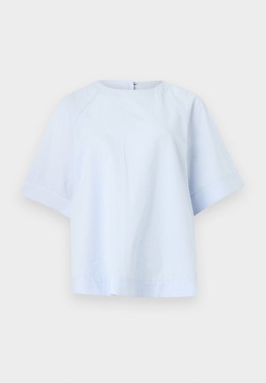 Lyseblå kortærmet bluse med rund halsudskæring og subtilt tekstureret stof, vist på en ensfarvet hvid baggrund.
