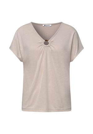 Blouse beige à manches courtes avec col en V, détail froncé et anneau circulaire en écaille de tortue à l'encolure.