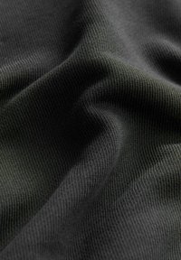 Tejido negro texturizado con un patrón acanalado, que muestra un material suave y flexible que cae de manera suave y capta la luz de forma sutil.