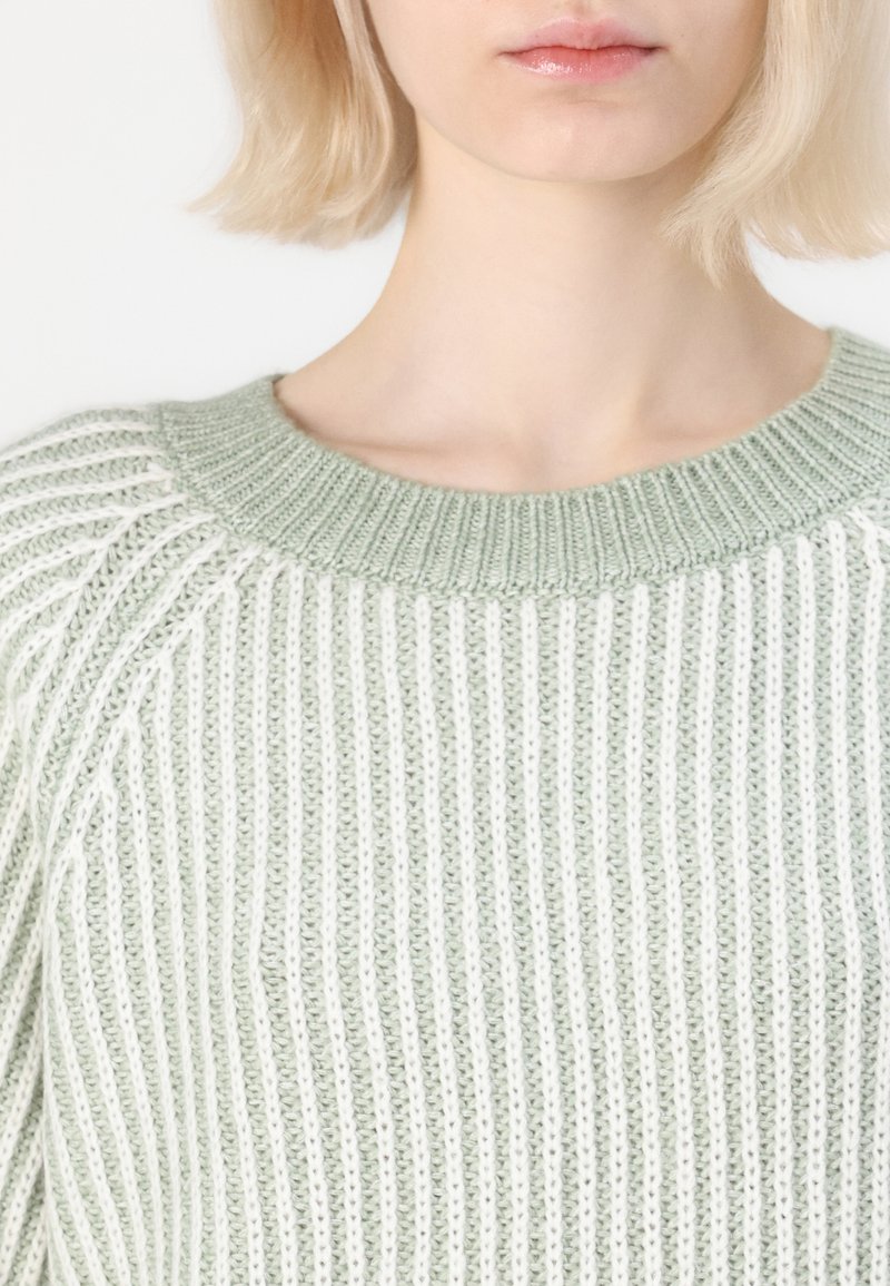 Lichtgroene gebreide trui met een ribbelstructuur en een wijde ronde hals. De stof heeft afwisselend verticale strepen in een zachte tint.