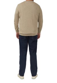 Beige trui met een ronde hals en lange mouwen, gecombineerd met donkerblauwe broek. Van achteren weergegeven, met de nadruk op strakke lijnen en een eenvoudig ontwerp.