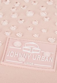 Világos rózsaszín hátizsák texturált felülettel és átlátszó vízcseppekkel. A hátizsákon fehér "JOHNNY URBAN JUNIOR" márkanevű címke található, valamint puha, sima részletek.