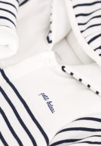 Polo z bawełny w paski w kolorze białym i granatowym, z zapięciem na guziki i haftowaną nazwą marki "petit bateau" z przodu.