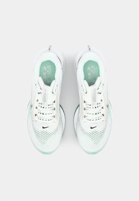 Baskets de sport blanches avec une tige en maille, accents vert menthe, lacets doux et semelle texturée ; présentent le logo Nike sur la languette et sur le côté.