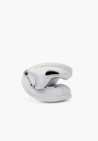 Scarpa bianca in pelle con una texture morbida, forma arrotondata e chiusura in Velcro. Presenta un'apertura elastica e una suola in gomma flessibile.
