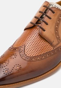 Pantof brown din piele cu design perforat, finisaj neted, vârf ascuțit și șireturi maro. Dispune de detalii decorative tip brogue.