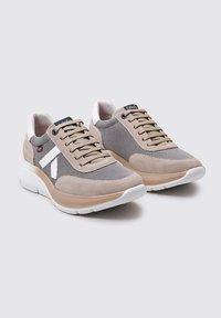 Zapatillas deportivas beige con parte superior de malla y ante, acentos en blanco, punta redondeada y suela de goma gruesa. Cordones en un patrón entrelazado.