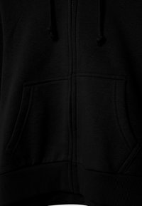 Haut à capuche zippé noir en tissu doux. Doté de deux poches avant, de poignets et d'un ourlet en bord-côte épais ; le design est simple et sans ornements.