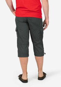 Charcoal cargo capri pants with side pockets, knee-length, textured fabric, and adjustable cuffs, worn with brown loafers.